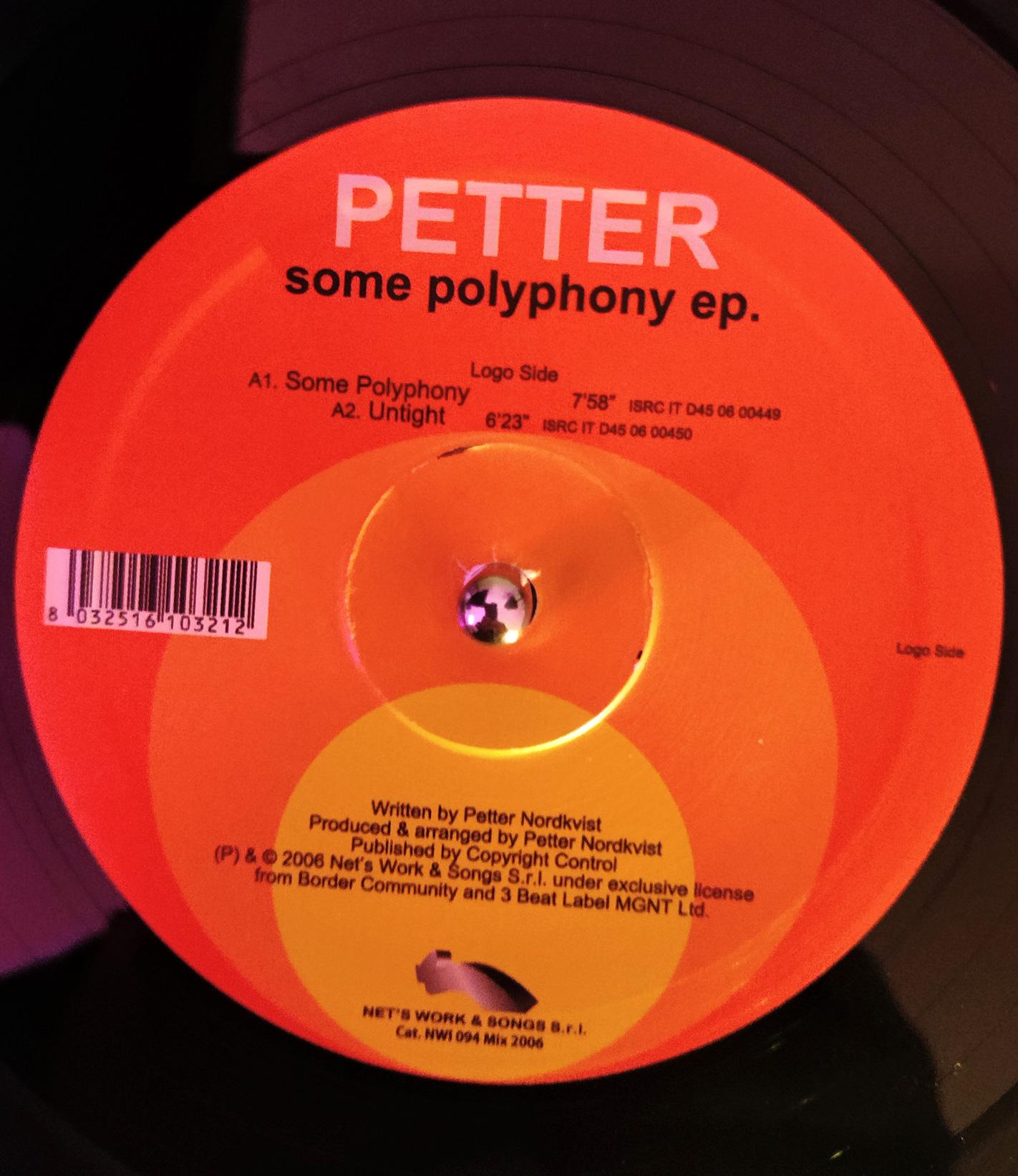 Closeup of a 12" vinyl record with its center label. The label displays information on an orange and yellow background.
